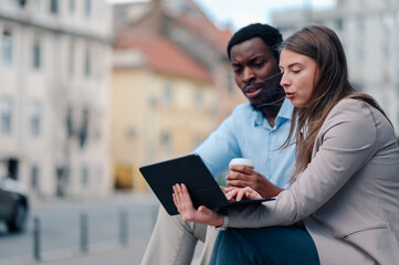 Businesspeople working outdoors using digital tablet and drinking coffee