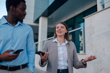 Businesspeople walking and talking holding smartphones in their hands