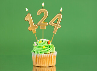 Number 124 birthday candle - Cupcake on a green background