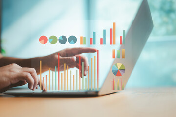 Hands pointing at colorful data charts on laptop screen, symbolizing business intelligence, digital...