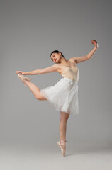 Graceful Ballerina in Studio: Elegant dance pose with arms raised ballet shoes and white skirt