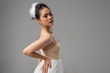 Graceful ballerina posing in a beige leotard and white tutu with feathered hairpiece looking up