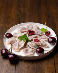 Traditional dumplings with cherry on white plate
