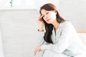 起きてベッドの上で頭痛を訴える女性