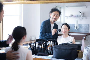 Hair and makeup man and woman with makeup brushes Makeup image Looking in the mirror