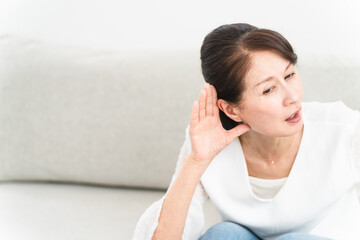 耳に手を当てて聞きかえす熟年女性