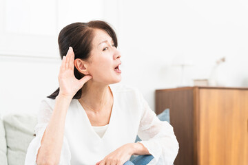 耳に手を当てて聞きかえす熟年女性