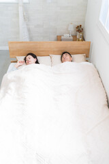 ベッドの上で眠る夫婦