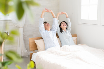 起きてベッドの上で伸びをする夫婦