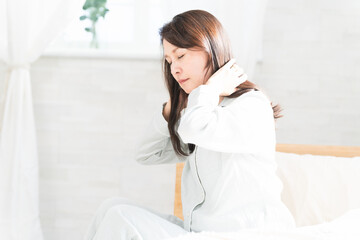 起きてベッドの上で肩を揉む女性