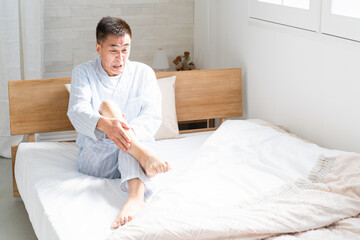 起きてベッドの上で足が攣っている男性