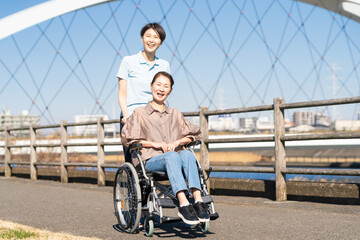 車椅子を押して散策する女性と介護士
