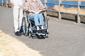 車椅子を押して散策する熟年夫婦と介護士