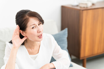 耳に手を当てて聞きかえす熟年女性