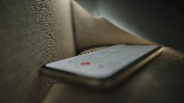 Hidden mobile phone is using voice recording app to capture conversation. Located under pillow in home couch smartphone is secretly hearing and listening. Investigation cheating wiretapping operation