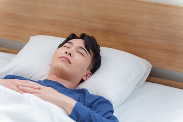 朝ベッドで寝る男性