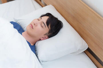 朝ベッドで寝る男性