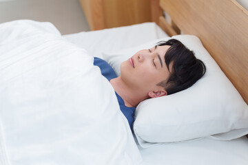 朝ベッドで寝る男性