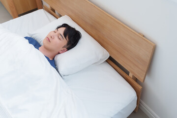 朝ベッドで寝る男性