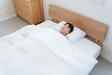 朝ベッドで寝る男性