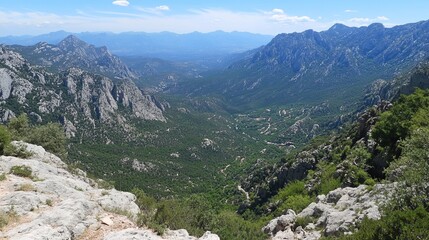 Panoramic view of a valley nestled between majestic mountain ranges, lush greenery, and a glimpse of a small village