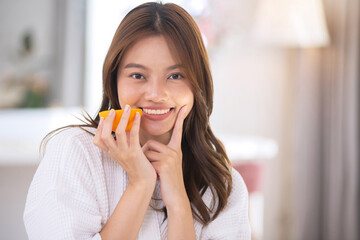 A beautiful Asian woman shows off her regular intake of halved oranges to boost her vitamin C intake. Nourishing your skin with natural