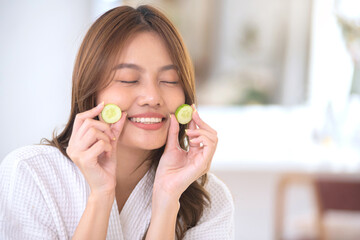 Beautiful Asian woman shows off cucumber slices to nourish her skin regularly, nourishing your skin with natural ingredients