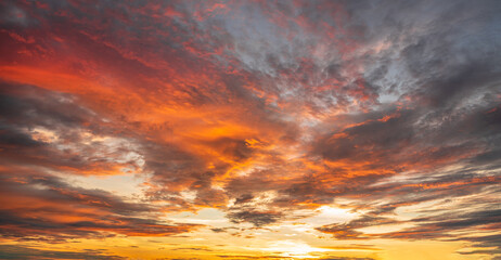 Vibrant fiery sunset over the ocean with silhouettes of cargo ships on the horizon, painting the...