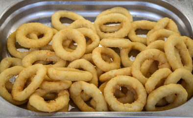 Delicious crispy onion rings served in a stainless steel tray, perfect for appetizers or party...