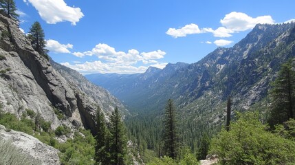 Fototapeta premium Majestic mountain valley scene with towering rock faces, lush green forests, and a vibrant blue sky dotted with fluffy white clouds. A breathtaking vista of nature's grandeur
