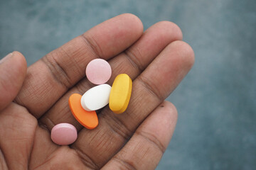 Hand holding various colorful pills for health and wellness