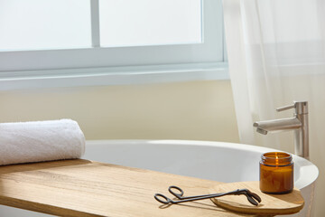 Bathroom corner with white tub, wood tray and round table. Window light softens the scene, leaving...