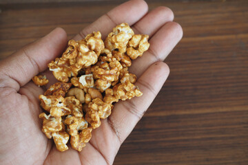 Hand holding freshly made caramel popcorn on wooden surface