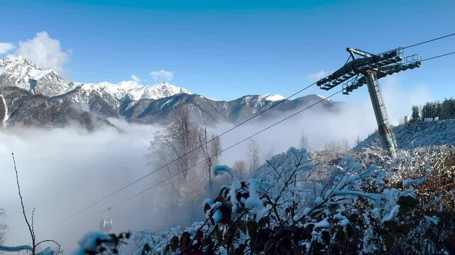 Snow-covered lift tower rises over foggy slopes with mountain backdrop in Tufandag. Gabala, Azerbaijan