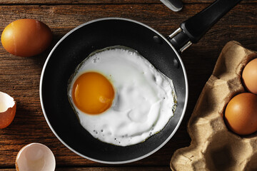 Fresh Egg Being Fried in a Black Pan on a Wooden Table Surface