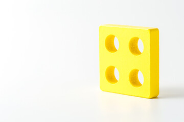 Bright Yellow Square Block with Circular Holes on White Background