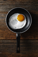 Fried Egg in Black Frying Pan on Rustic Wooden Table Surface