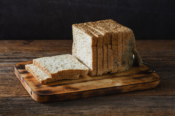 Sliced Whole Wheat Bread on Wooden Cutting Board with Dark Background