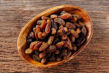 Organic Dried Raisins in a Wooden Bowl Resting on Rustic Surface