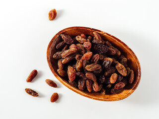 Dried raisins in a wooden bowl on a plain white background