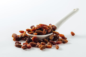 Fresh Organic Raisins Poured from Spoon on White Background