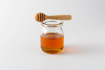 Glass Jar with Honey and Wooden Dipper on Light Background