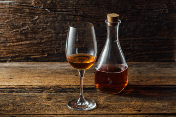 Elegant Glass of Amber Liquid Next to a Vintage Bottle on Wood Table