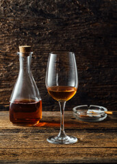 Elegant Glass of Amber Liquid Next to Decanter and Ashtray