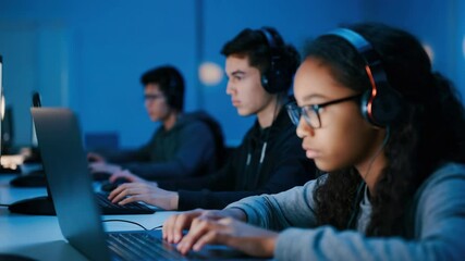 Focused young girl coding on laptop, with headphones in blue-lit room - Powered by Adobe