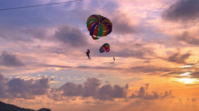 8 July 2025 Parasailing at and magnificent sunset on Patong Beach on the island of Phuket Thailand. People standing around watching the colourful sunset