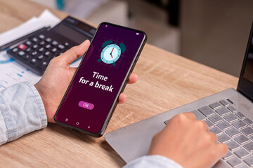 Take a break from your activity or phone concept. Person holding smartphone with time for a break notification.
