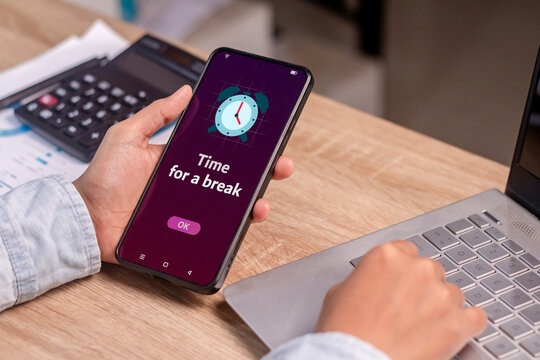 Take a break from your activity or phone concept. Person holding smartphone with time for a break notification.