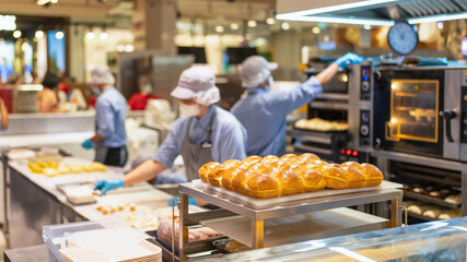 A lot of ready-made fresh bread in a bakery with blurred bakery shop in wholesale store with baking machine, selective focus . Bread making business. 