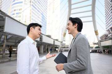 Two asian businessmen discussing a project in a modern city